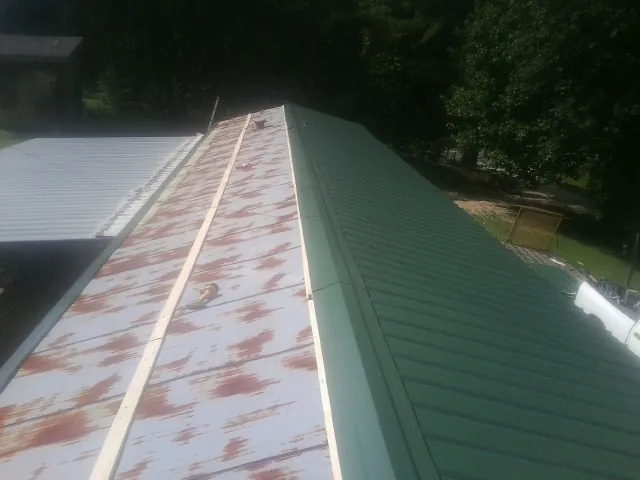 Old rusted panels beside newly installed green metal roofing — Wind Damage Roof Repair by Roofing Brothers in Peculiar