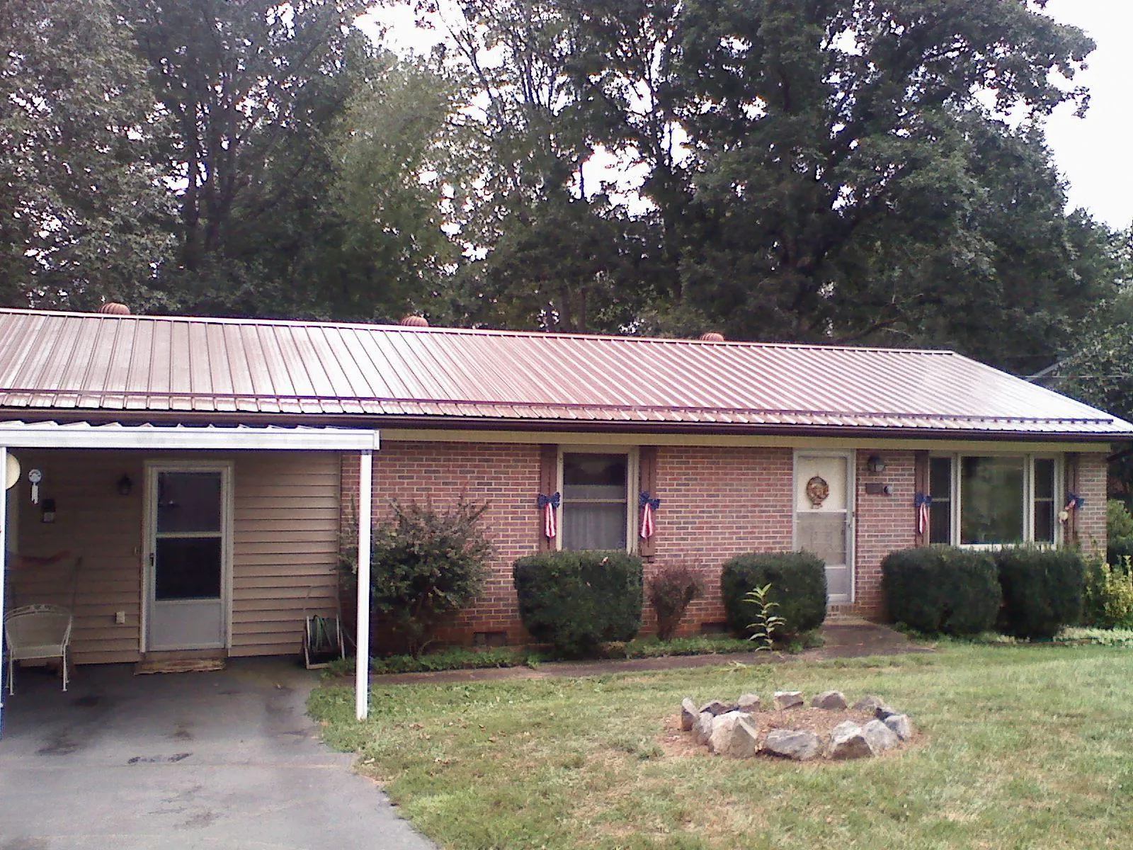 Bronze metal roof and carport on a brick ranch home — Roof Repair work by our crew in Peculiar